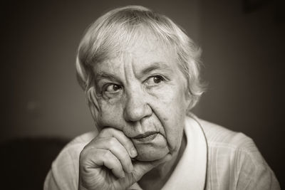 Close-up of thoughtful senior woman with hand on chin