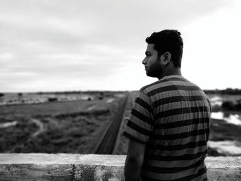 Man looking away on field against sky