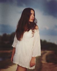 Beautiful young woman standing against sky