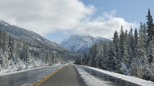 Road amidst snowcapped mountains against sky during winter