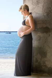 Side view of pregnant woman standing at beach