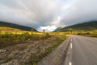 Surface level of country road against cloudy sky