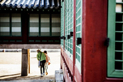 Rear view of woman standing in front of building