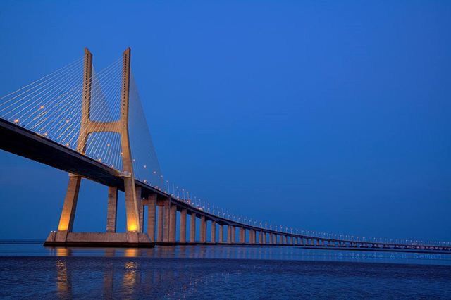 built structure, clear sky, architecture, connection, bridge - man made structure, water, engineering, blue, suspension bridge, bridge, sea, copy space, waterfront, transportation, low angle view, river, long, cable-stayed bridge, travel destinations, outdoors