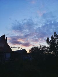 Silhouette buildings in town against sky at sunset