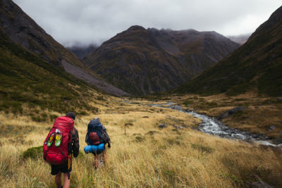 Rear view of friends standing on mountain against sky