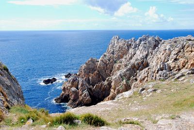 Scenic view of sea by cliff against sky