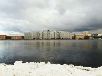 Buildings by lake against sky in city