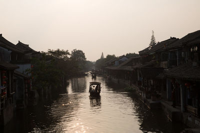 High angle view of boats sailing on river amidst houses against clear sky