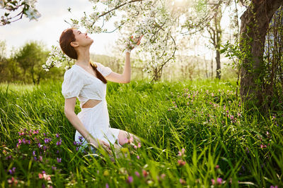 Side view of young woman standing on grassy field