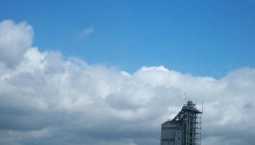 Low angle view of modern building against cloudy sky