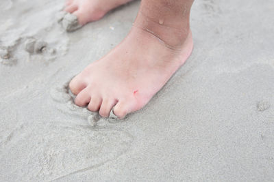 Low section of person standing on wet sand