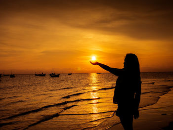 Silhouette woman standing at beach during sunset