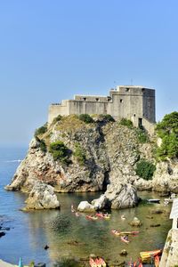 Buildings by sea against clear blue sky