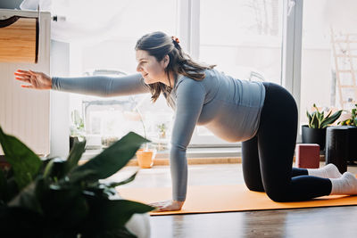 Side view of young woman exercising at home