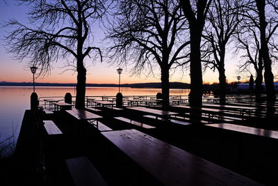 Silhouette trees by sea against sky during sunset