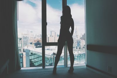 Silhouette man standing by window in city