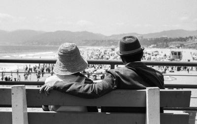 Rear view of men sitting on railing