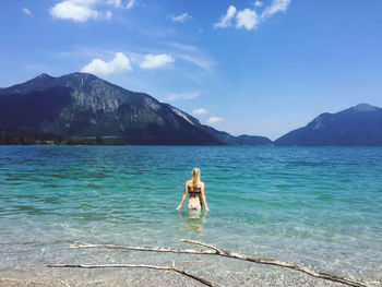 Man in sea by mountains against sky