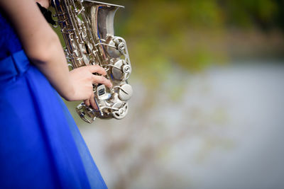 Midsection of young bride playing saxophone in park