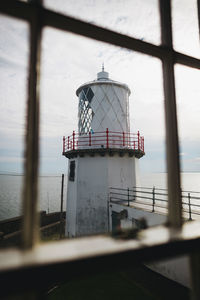 Lighthouse by sea against sky