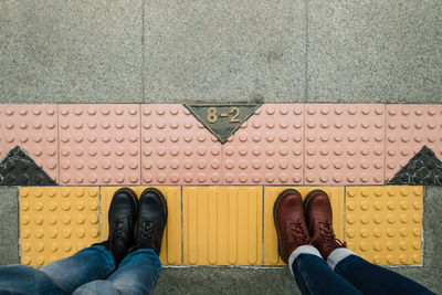 Low section of people standing on footpath by street