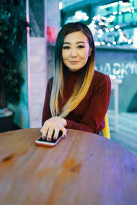 Portrait of smiling young woman sitting on table