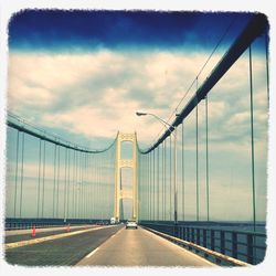 Bridge over river against cloudy sky