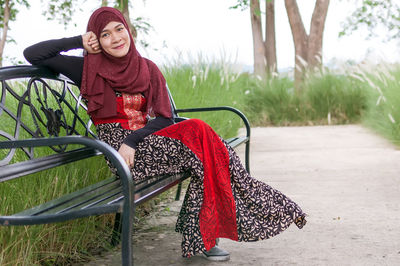 Portrait of woman in hijab sitting on bench at park