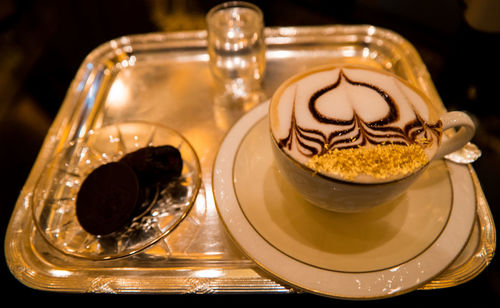 High angle view of coffee with froth art on serving tray