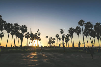 Silhouette palm trees on beach against sky during sunset