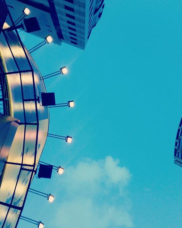 low angle view, architecture, built structure, building exterior, blue, modern, office building, tall - high, sky, city, tower, building, skyscraper, clear sky, directly below, no people, day, outdoors, lighting equipment, glass - material