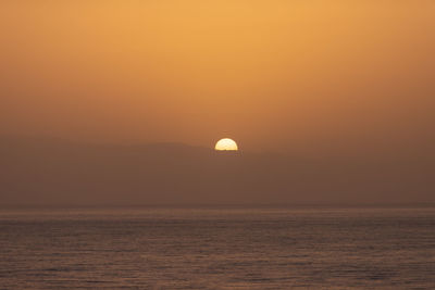 Scenic view of sea against orange sky