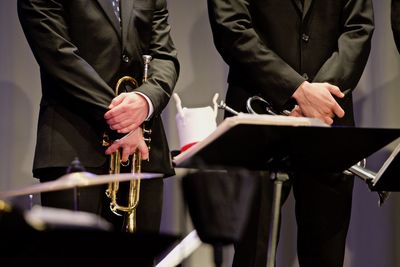 Midsection of men holding wind instruments while standing on stage