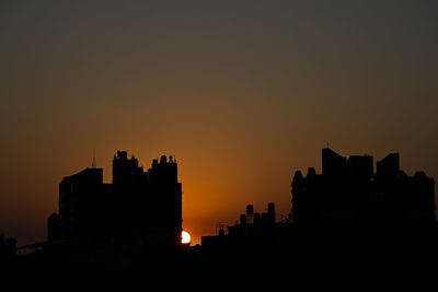 Silhouette buildings against sky during sunset