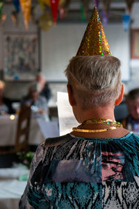 Rear view of senior woman wearing cap at birthday