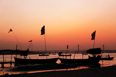 Silhouette boats moored in sea against sky during sunset