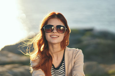 Portrait of smiling young woman against sea