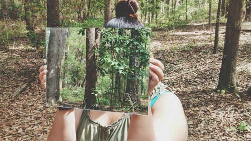 Woman standing on tree trunk in forest
