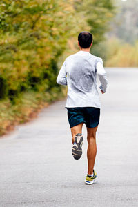 Male runner running in autumn park, on back sweat on clothes