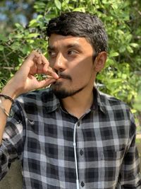 Portrait of young man holding smoking outdoors