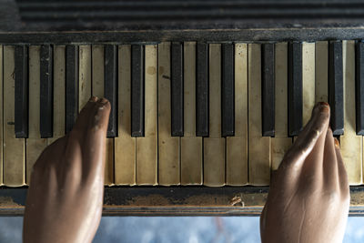 Vintage close-up of a mannequin's hands on the keyboard of an antique piano