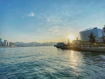 Scenic view of sea by buildings against sky during sunset