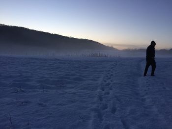 Man standing on snow covered landscape against sky