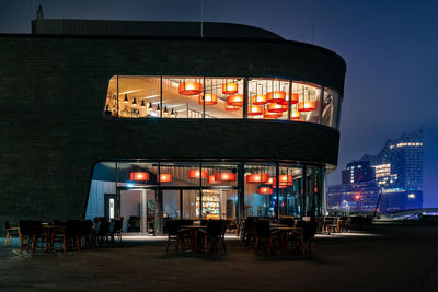 Illuminated restaurant against building at night