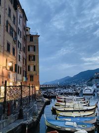 Sailboats moored on canal by buildings in city against sky