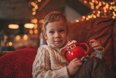 Portrait candid happy kid in knit beige sweater hold xmas mug with marshmallows and candy cane