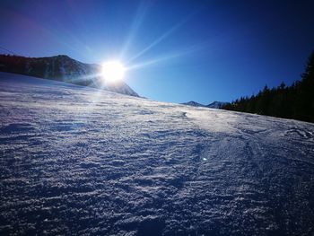 Snow covered landscape against blue sky