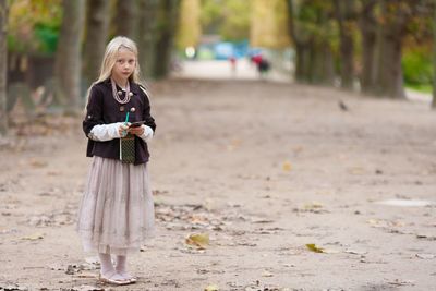 Portrait of girl holding note pad and pen while standing at park