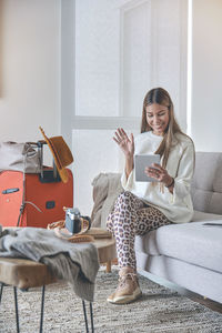 Young woman using mobile phone while sitting at home